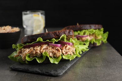 Photo of Delicious sandwiches with tuna and vegetables on light grey table, closeup