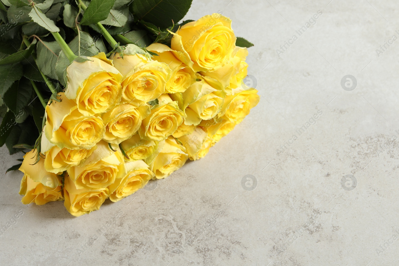 Photo of Beautiful bouquet of yellow roses on light grey table, above view. Space for text