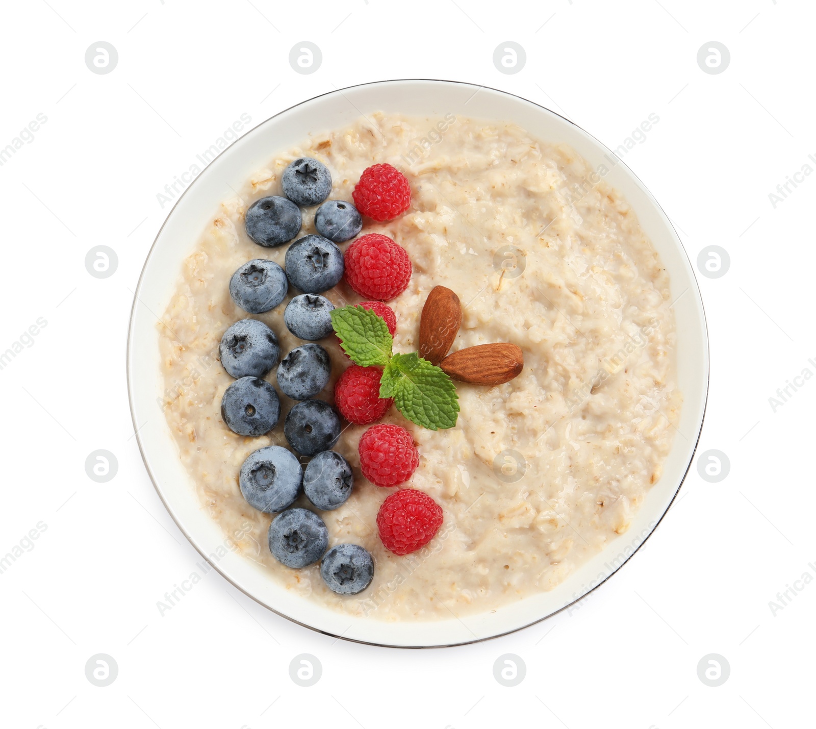 Photo of Tasty oatmeal porridge with raspberries, blueberries and almond nuts in bowl on white background, top view