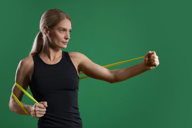 Athletic woman exercising with elastic resistance band on green background