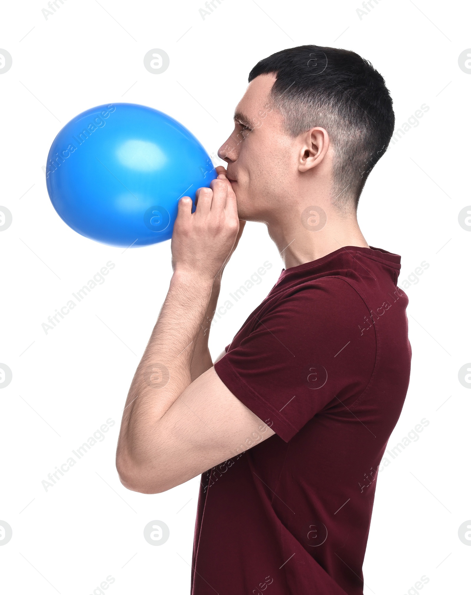 Photo of Young man inflating light blue balloon on white background