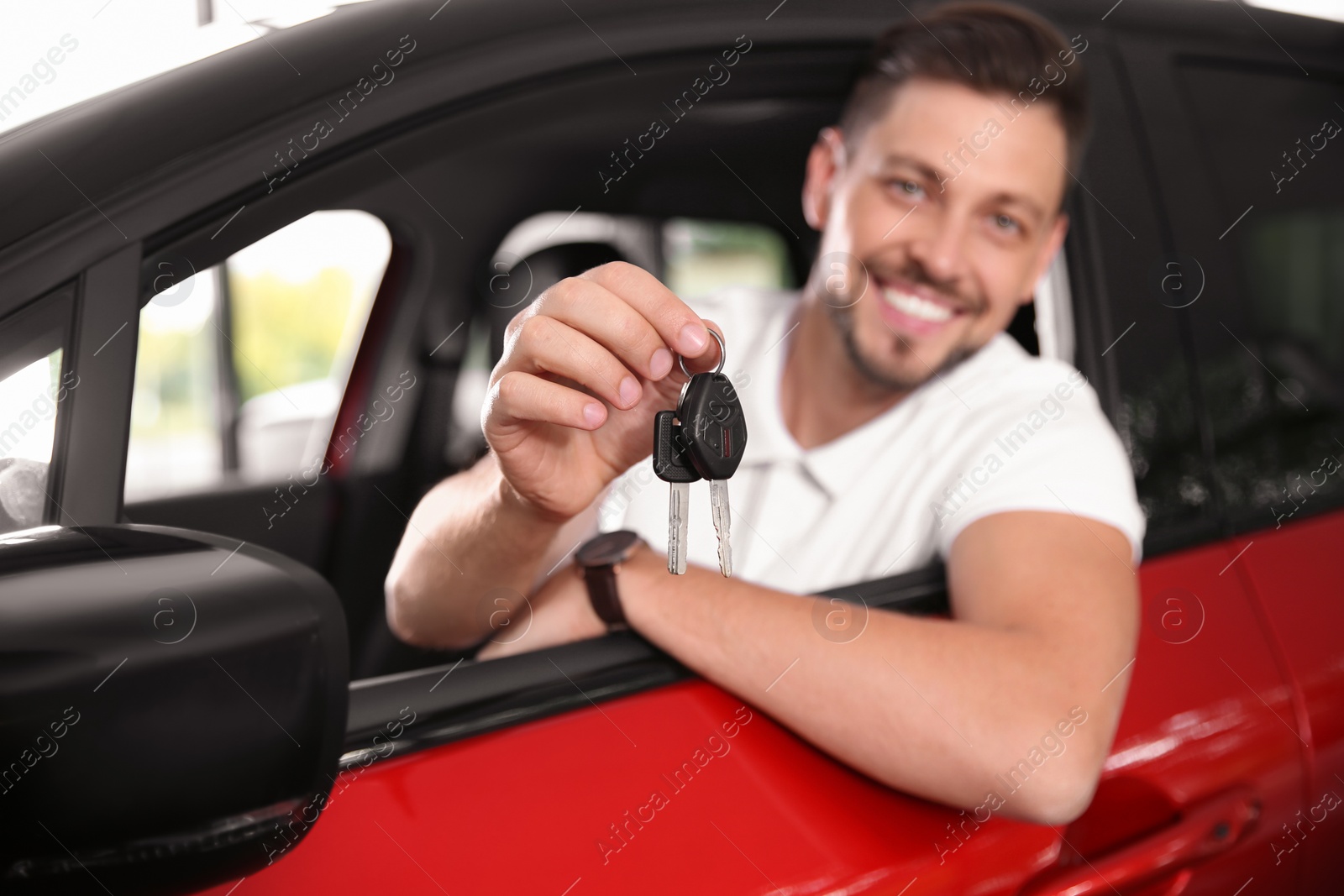 Photo of Happy man with car key sitting in driver's seat of new auto