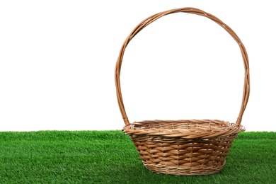 Photo of Empty wicker basket on green lawn against white background. Space for design. Easter item