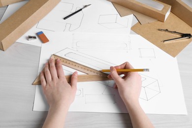 Photo of Woman creating packaging design at light wooden table, above view