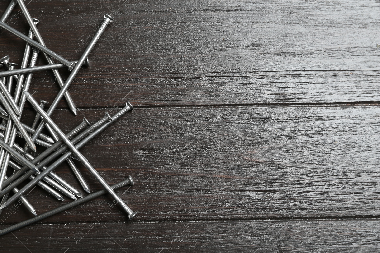 Photo of Many metal nails on wooden background, flat lay. Space for text