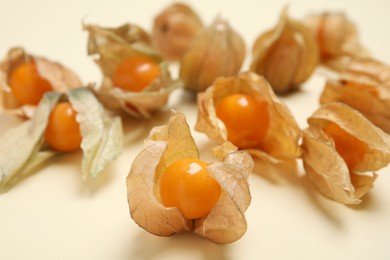 Photo of Ripe physalis fruits with dry husk on beige background, closeup