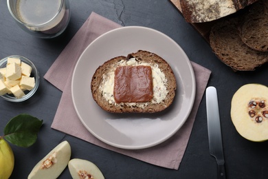 Photo of Bread with butter and quince paste on black table, flat lay