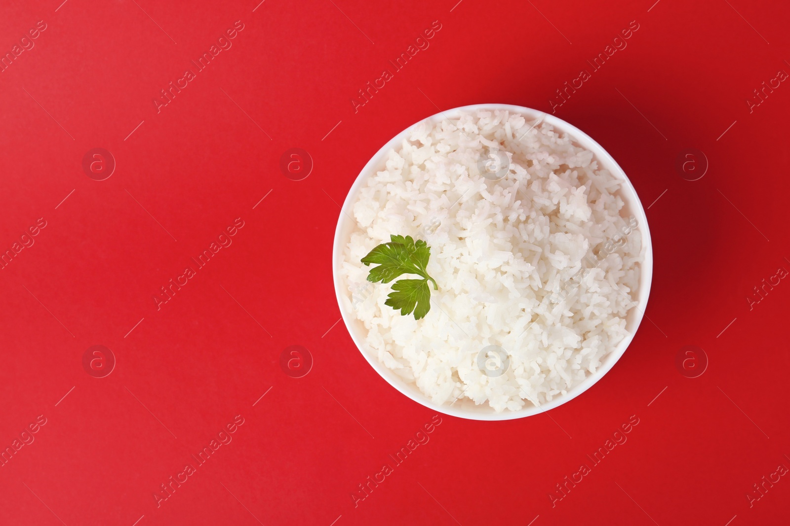 Photo of Bowl of boiled rice on color background, top view with space for text