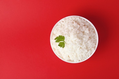 Photo of Bowl of boiled rice on color background, top view with space for text