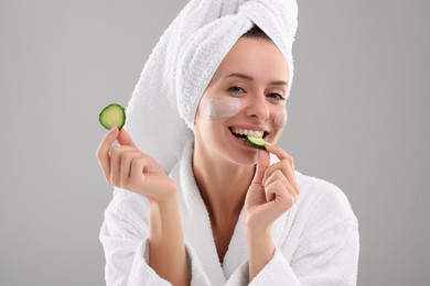 Photo of Woman with cosmetic product on her face and cucumber slices against grey background. Spa treatments