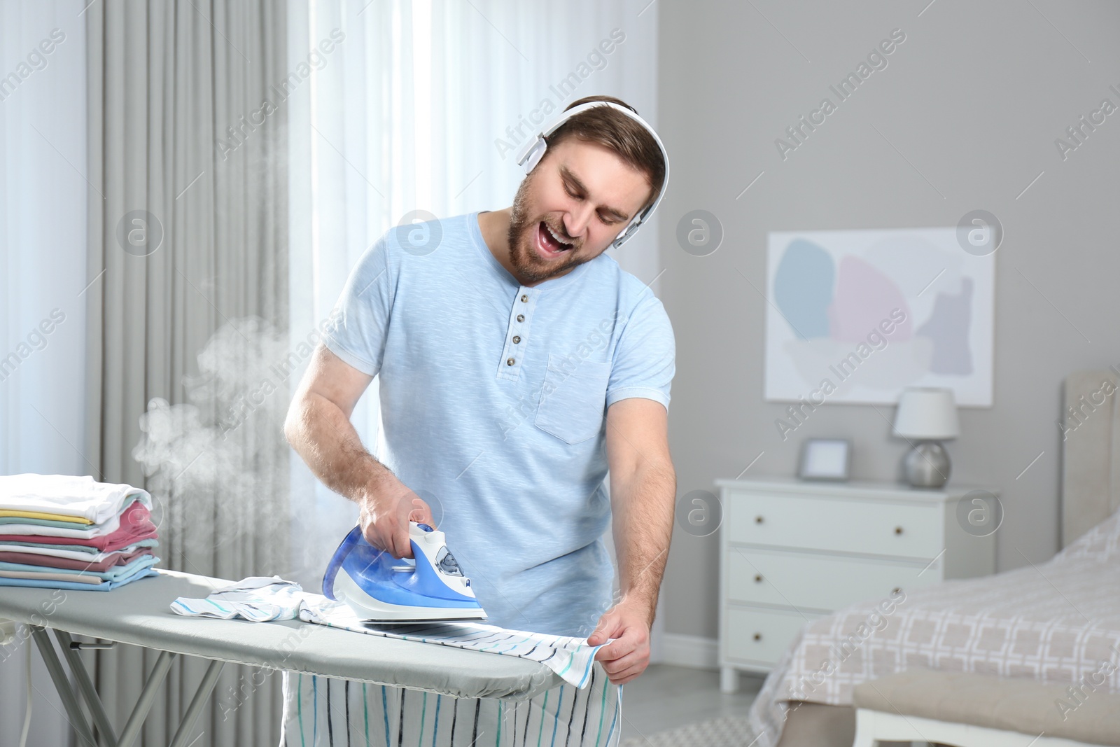 Photo of Man listening to music while ironing at home
