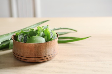 Photo of Bowl with sliced aloe vera leaves and space for text on wooden table