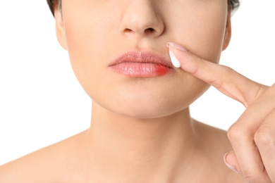 Woman applying cream onto lips on white background, closeup