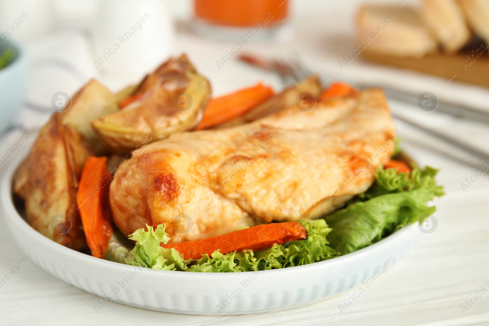 Photo of Delicious cooked chicken and vegetables on white table, closeup. Healthy meals from air fryer