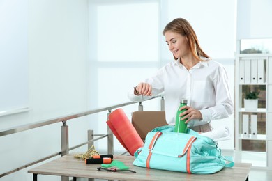 Photo of Businesswoman packing sports stuff for training into bag in office