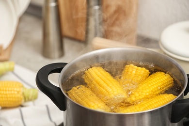 Photo of Stewpot with boiling water and corn cobs, closeup