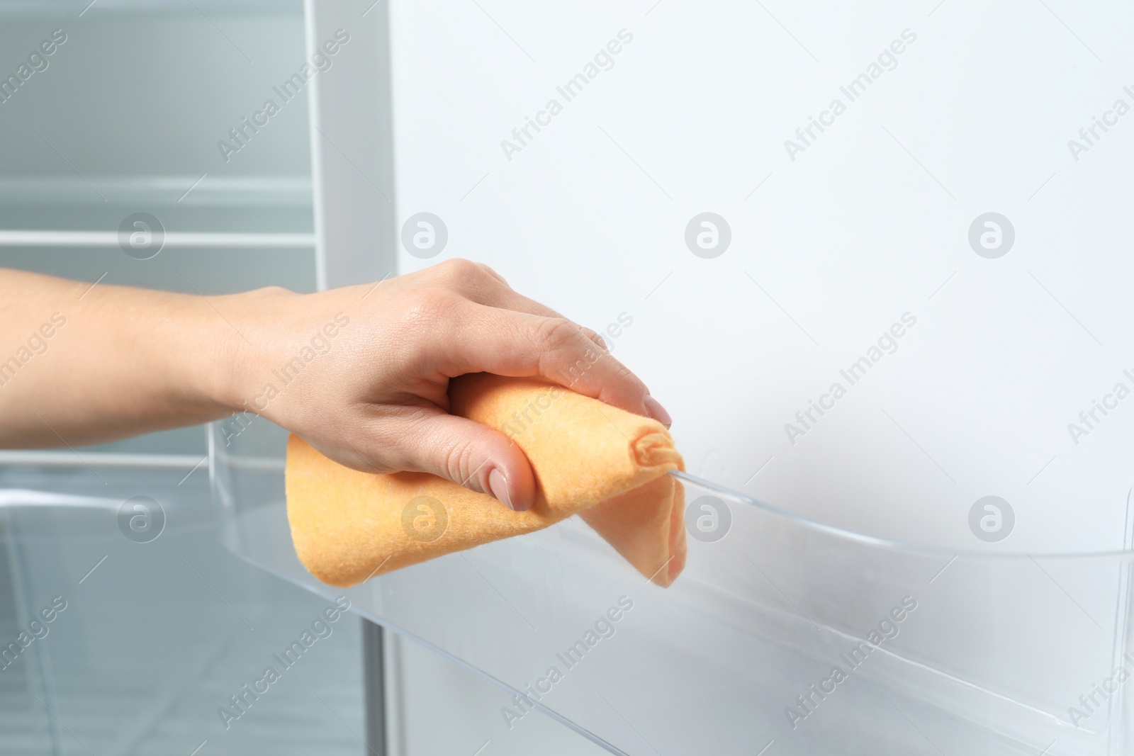 Photo of Woman cleaning empty refrigerator with rag, closeup