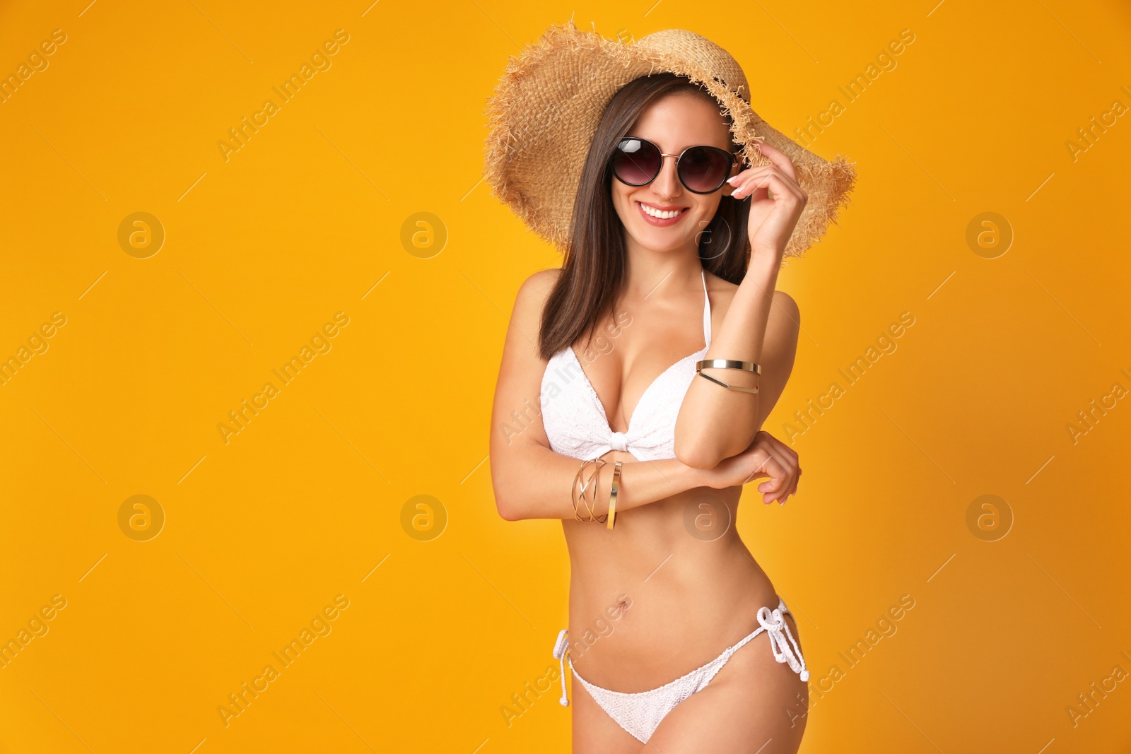 Photo of Pretty sexy woman with slim body in stylish  white bikini on orange background, space for text