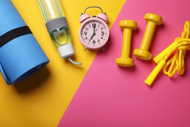 Photo of Flat lay composition with alarm clock, dumbbells and bottle of water on color background, space for text. Morning exercise