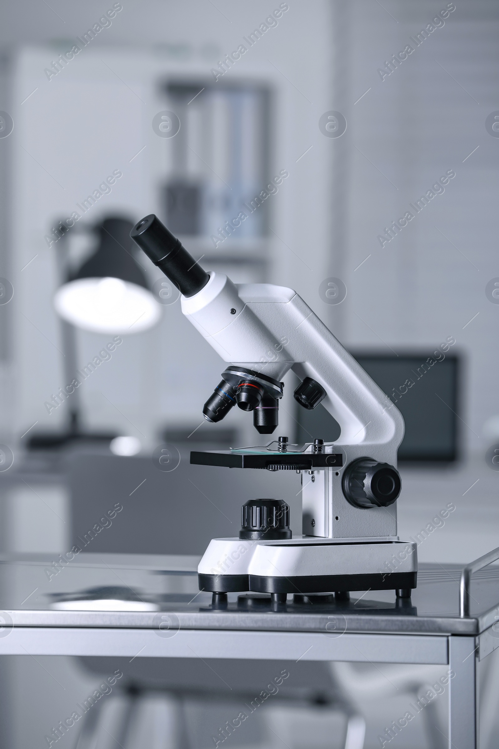 Photo of Modern medical microscope on metal table in laboratory