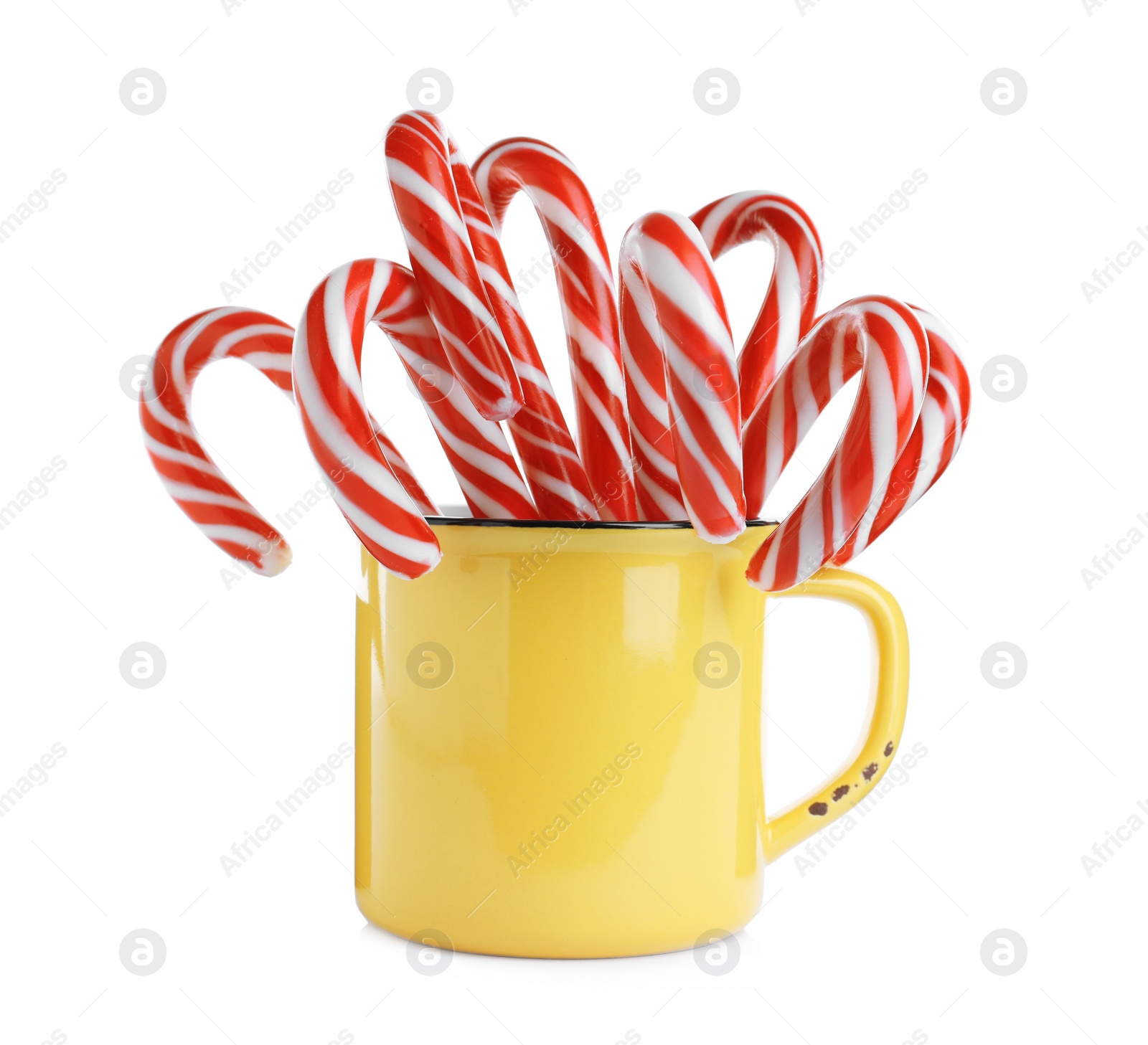 Photo of Yellow cup with sweet Christmas candy canes isolated on white