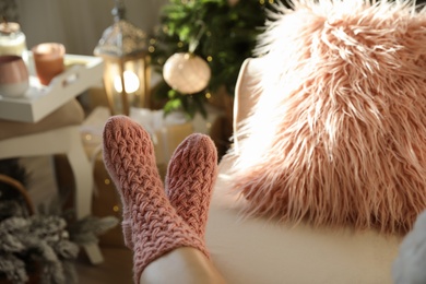 Woman wearing pink knitted socks in room decorated  for Christmas, closeup