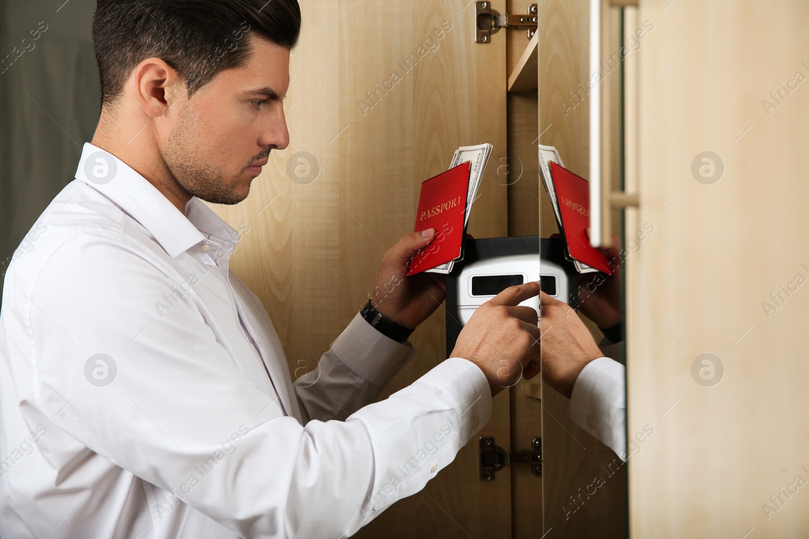 Photo of Man opening black steel safe with electronic lock at hotel