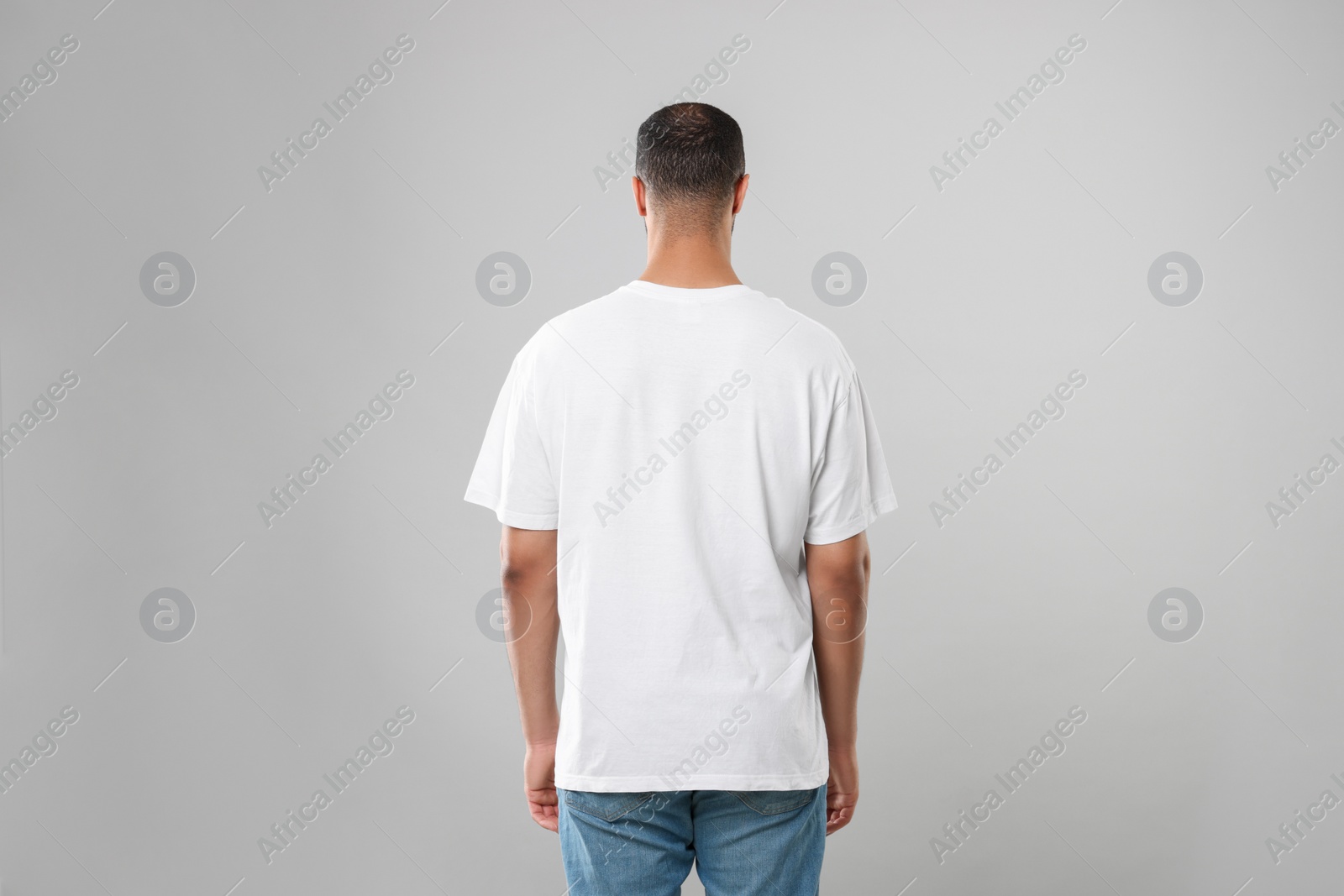 Photo of Man wearing white t-shirt on gray background, back view