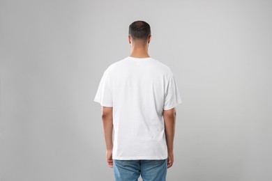 Man wearing white t-shirt on gray background, back view