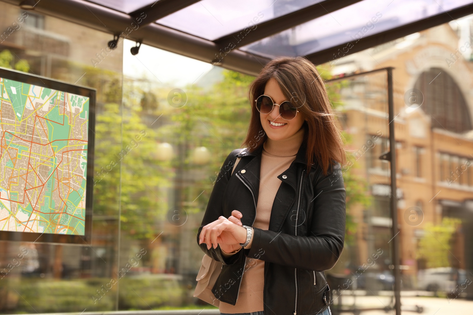 Image of Young woman checking time while waiting for public transport at bus stop