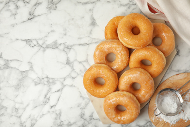 Photo of Delicious donuts on marble table, flat lay. Space for text