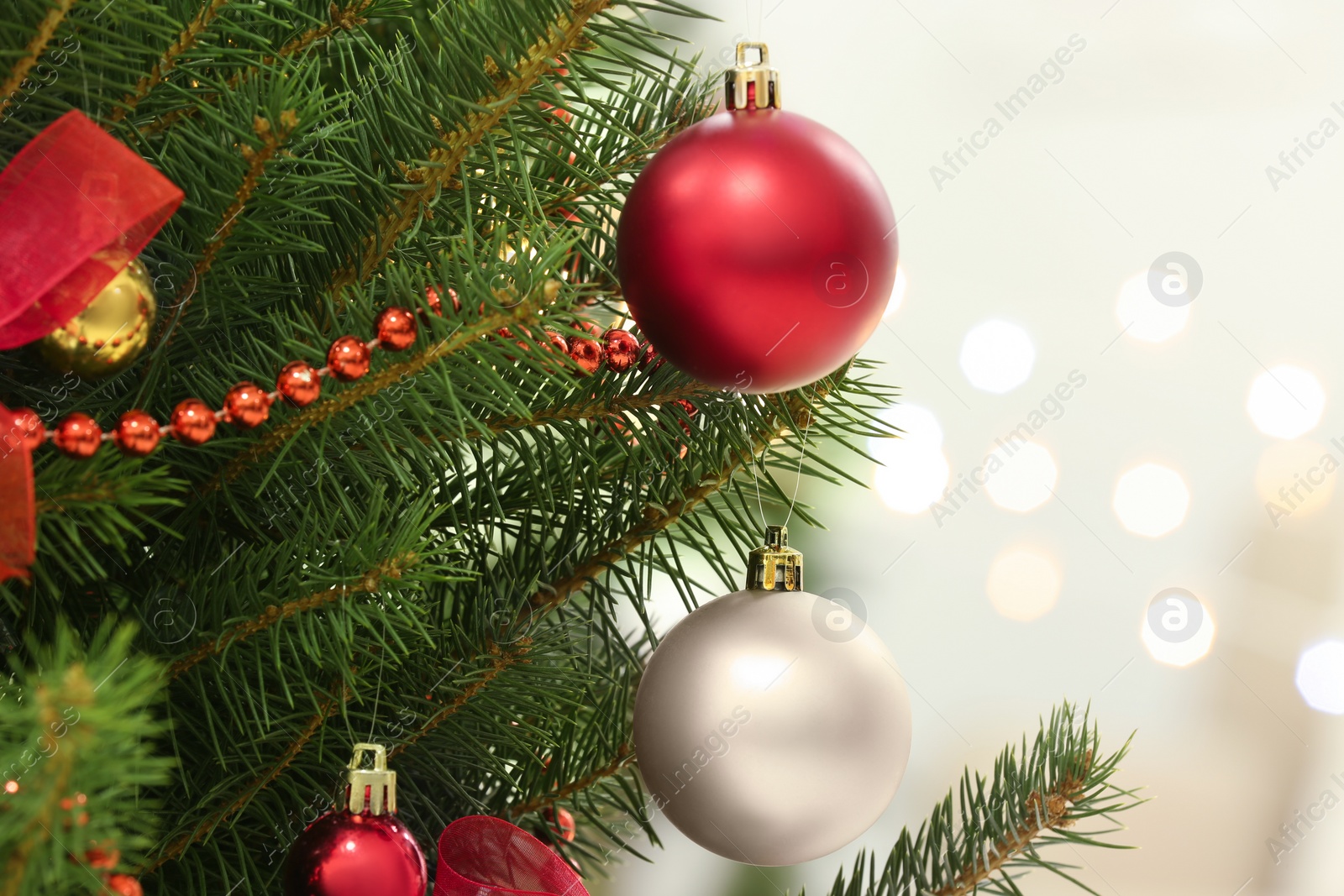 Photo of Color holiday baubles hanging on Christmas tree against blurred lights, closeup
