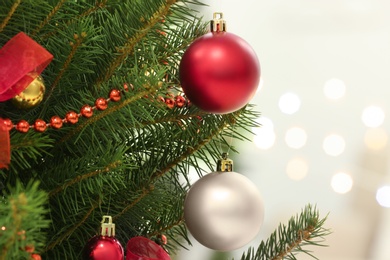 Photo of Color holiday baubles hanging on Christmas tree against blurred lights, closeup