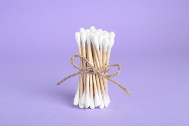 Bunch of wooden cotton buds on violet background