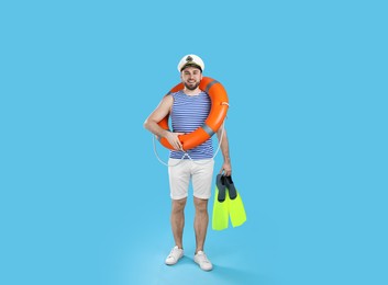 Photo of Sailor with ring buoy and swim fins on light blue background
