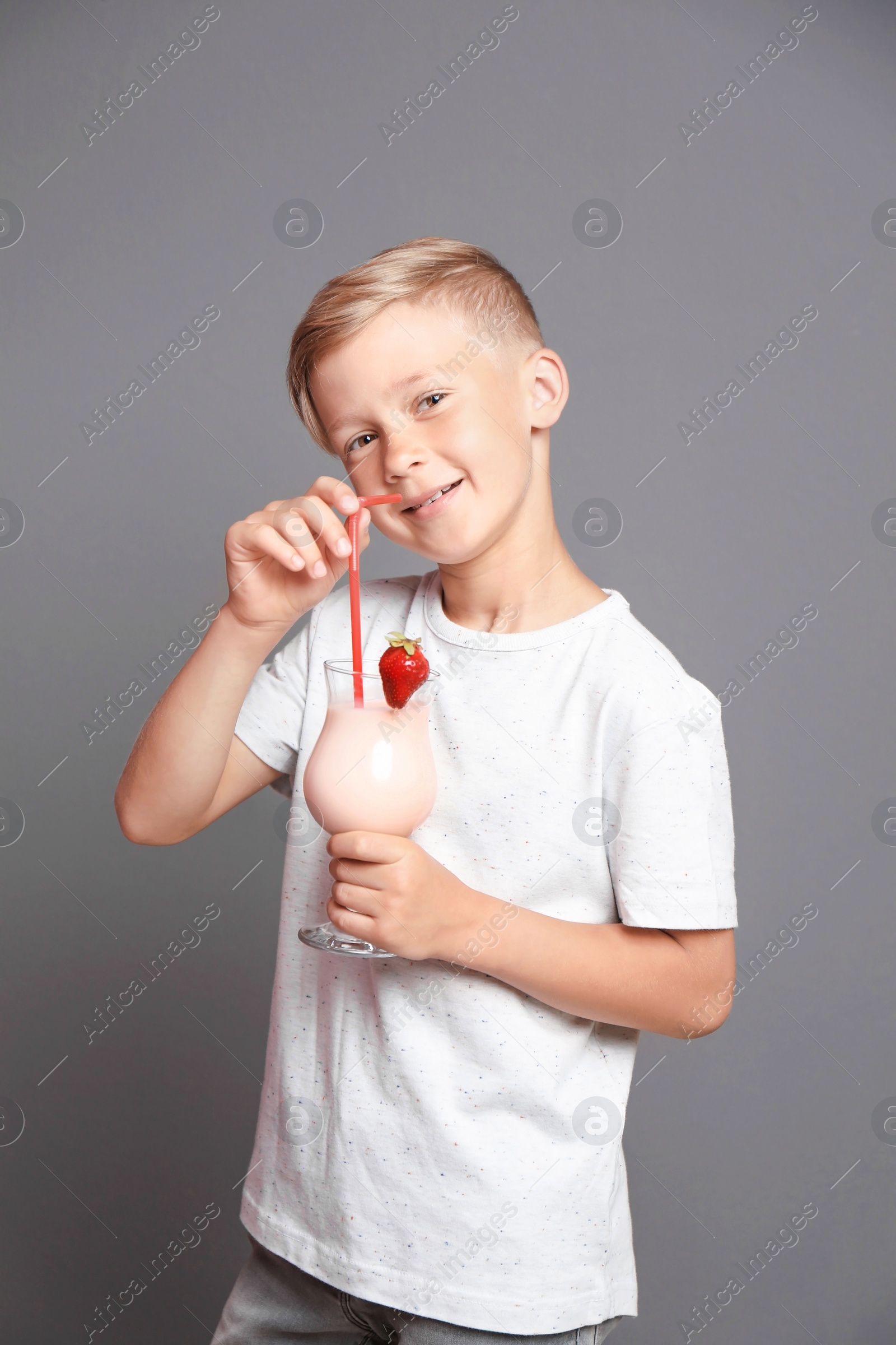 Photo of Little boy with glass of milk shake on grey background