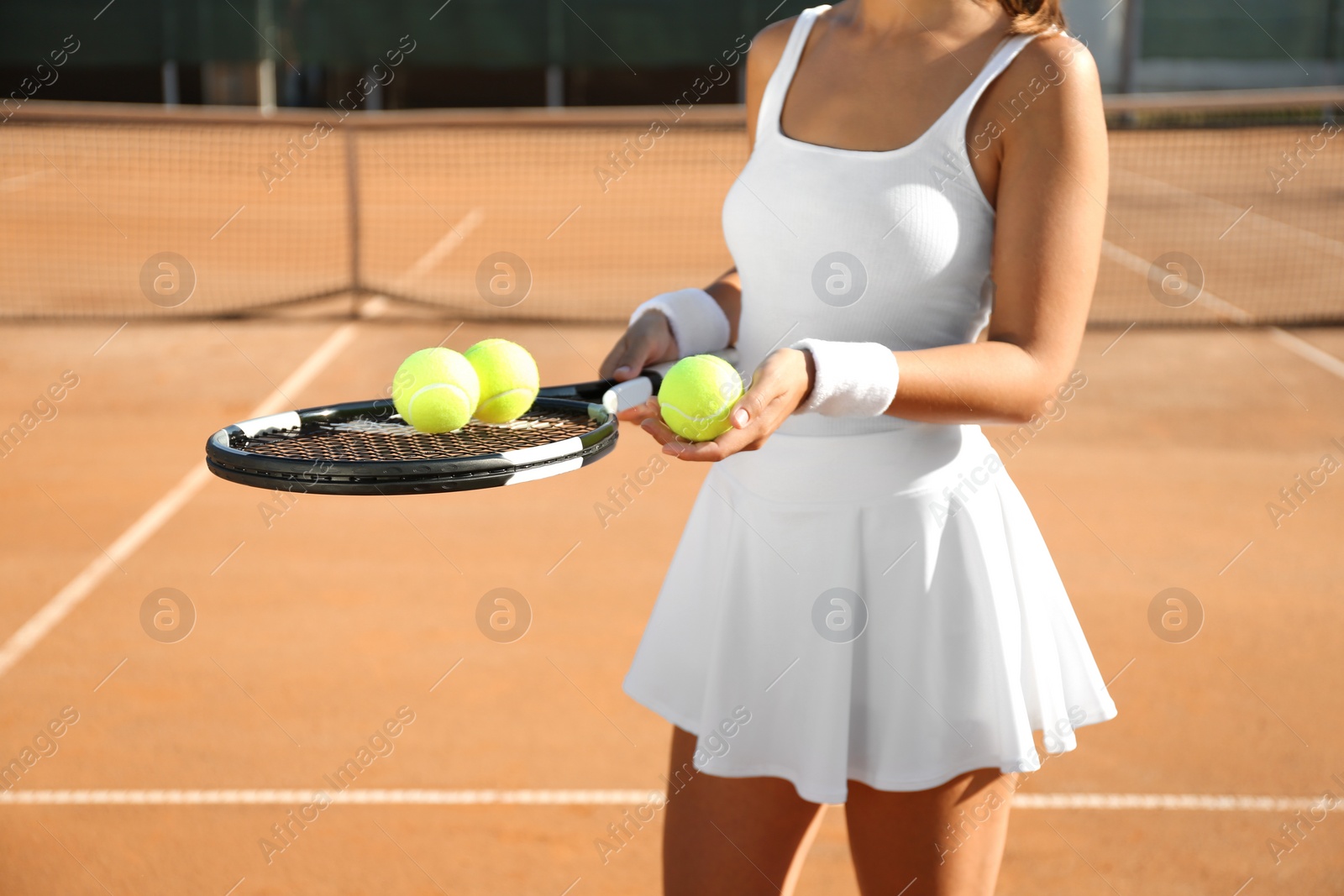 Photo of Sportswoman with racket and tennis balls at court, closeup