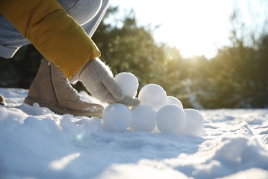 Photo of Woman rolling snowballs outdoors on winter day, closeup
