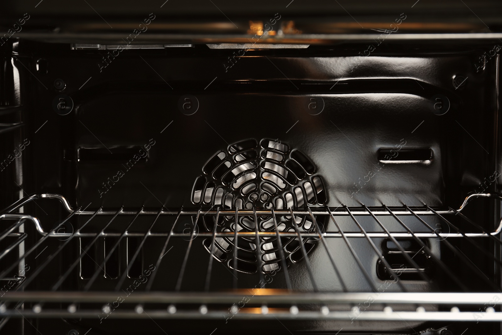 Photo of Open empty electric oven with rack, closeup. Inside view