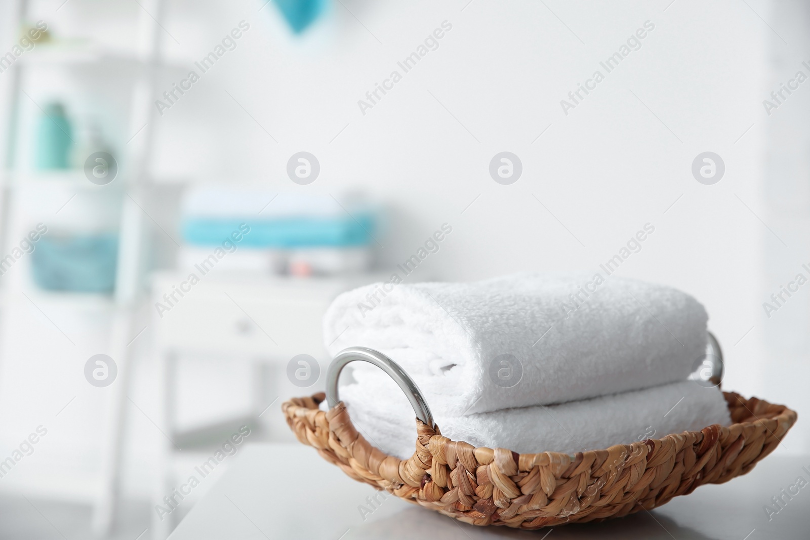 Photo of Wicker tray with towels on table against blurred background