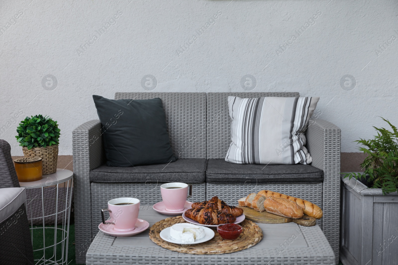 Photo of Outdoor breakfast with tea and croissants on rattan table on terrace