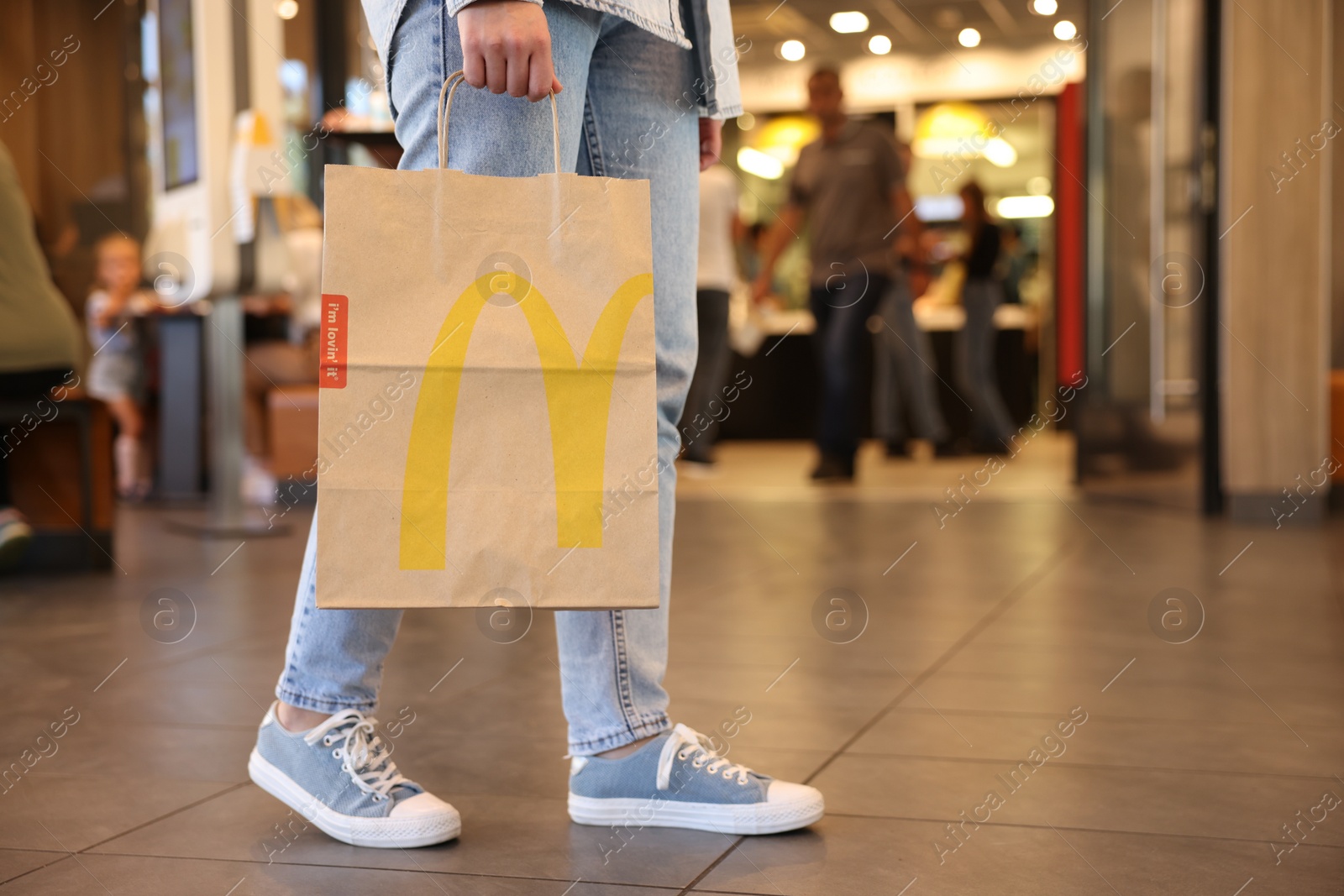 Photo of Lviv, Ukraine - September 26, 2023: Woman with McDonald's paper bag in cafe, closeup. Space for text