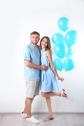 Young couple with air balloons near white wall