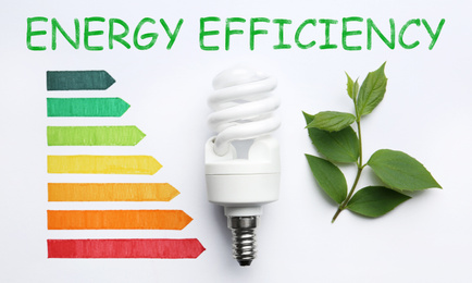 Image of Flat lay composition with energy efficiency rating chart, fluorescent light bulb and leaves on white background