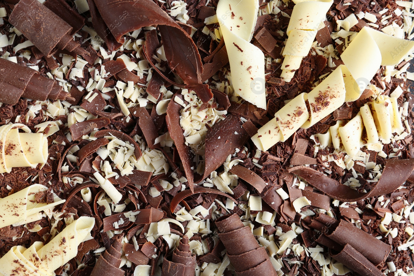 Photo of Yummy chocolate curls for decor as background, top view