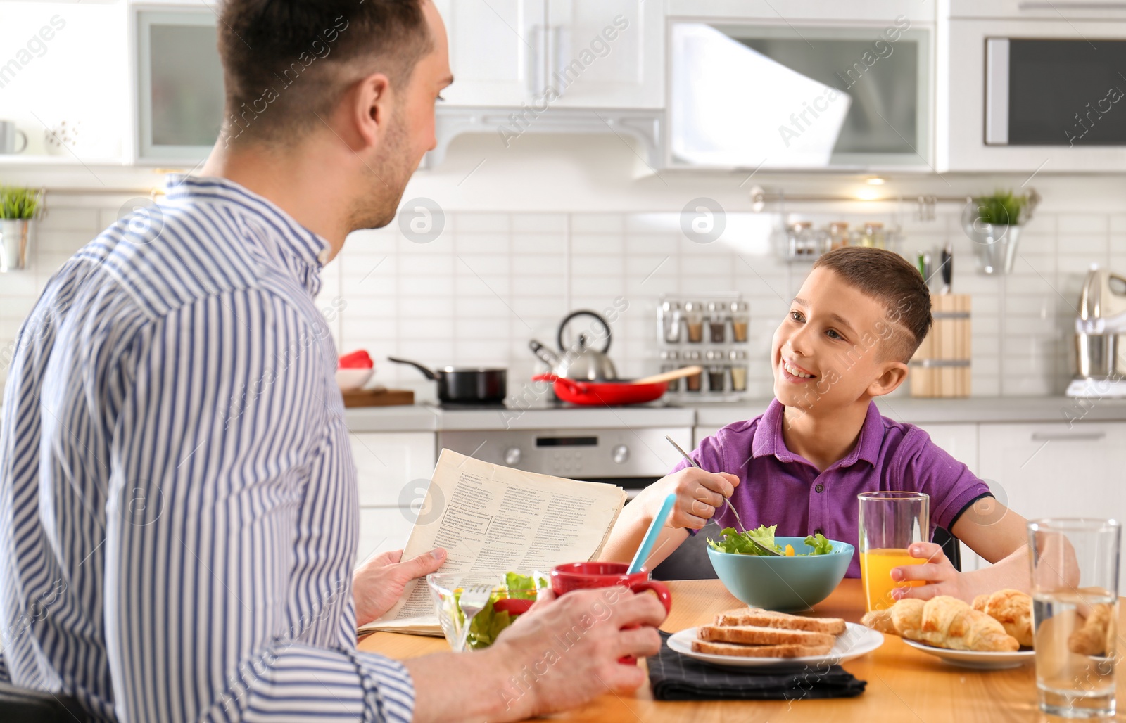 Photo of Dad and son having breakfast together in kitchen