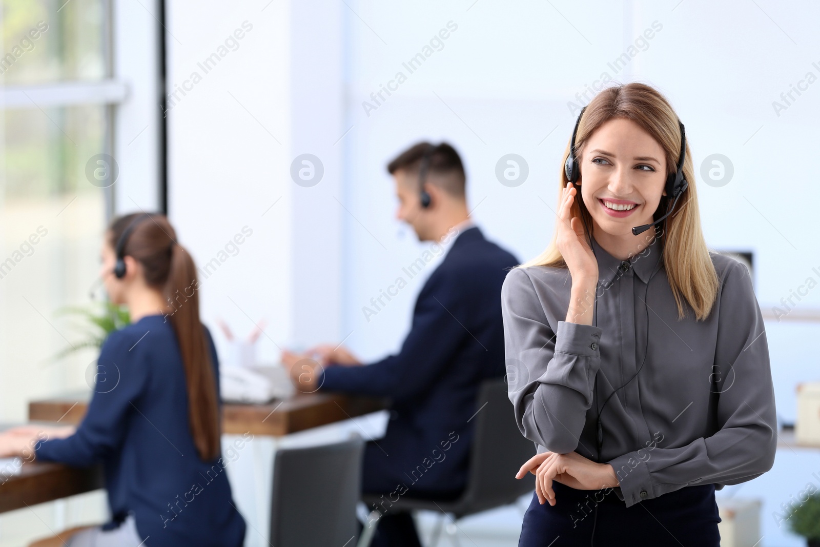 Photo of Young female receptionist with headset in office