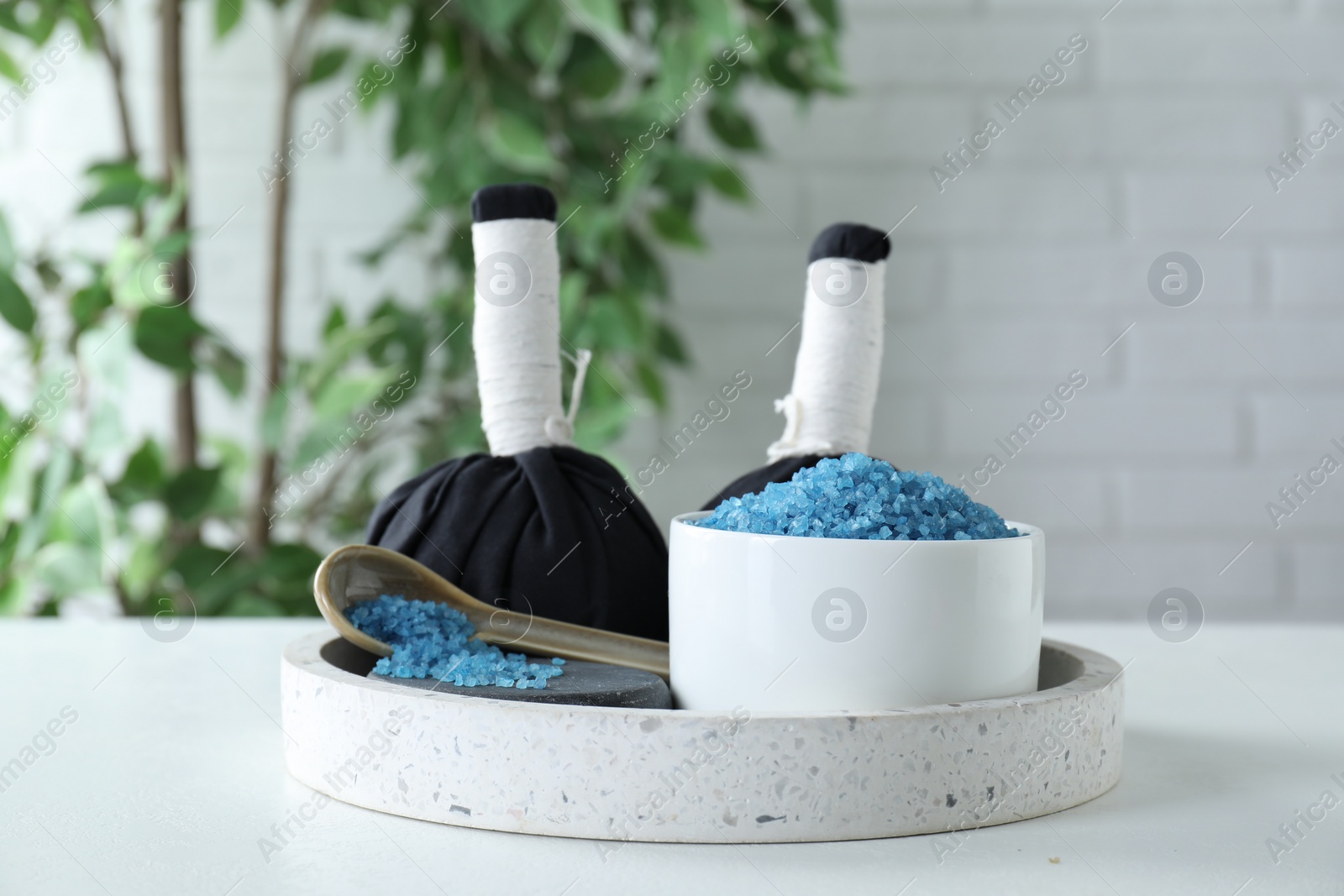 Photo of Blue sea salt and herbal bags on white table indoors