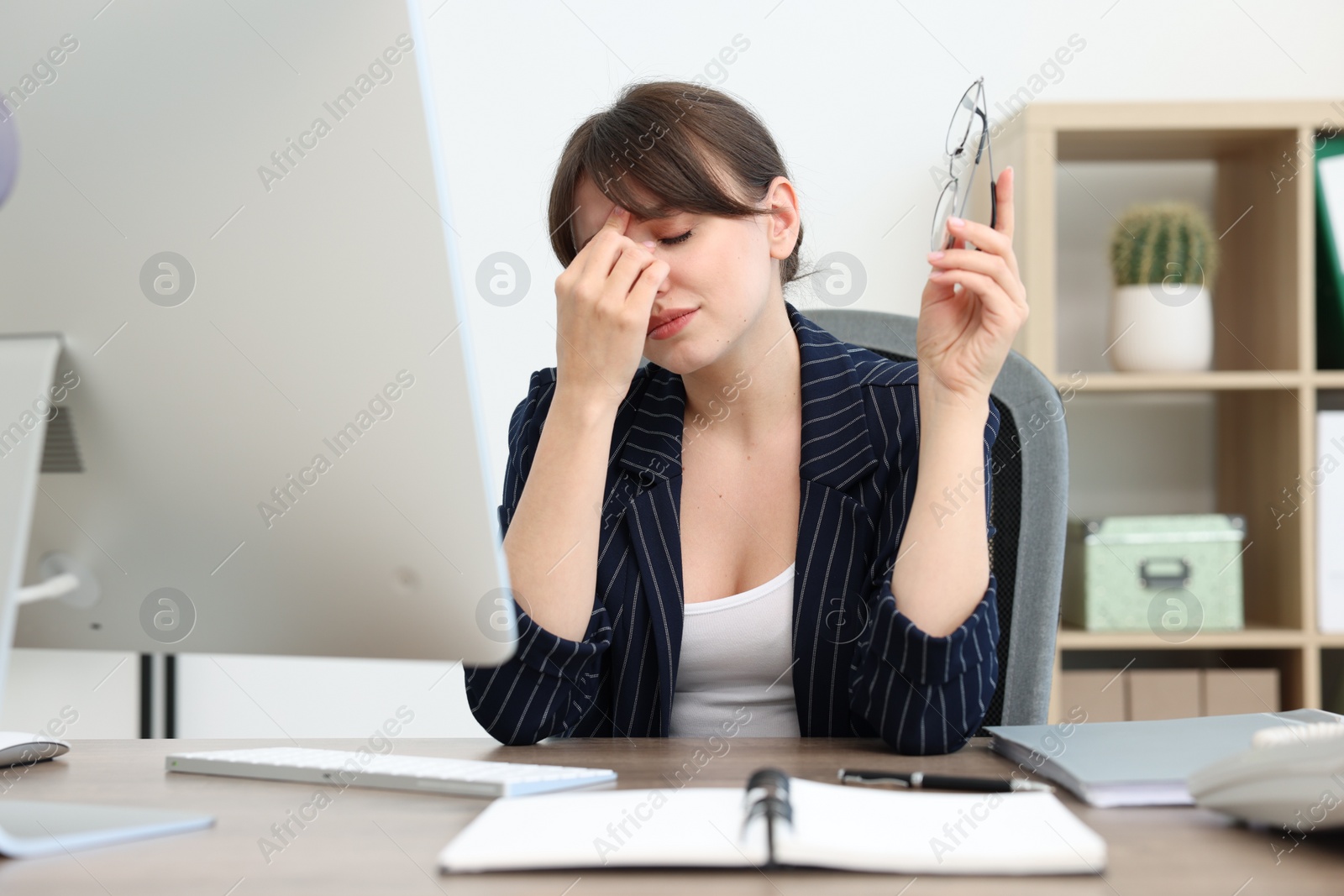 Photo of Overwhelmed office worker sitting at table with computer indoors