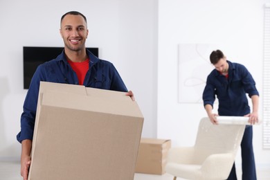 Male mover with cardboard box in house, space for text